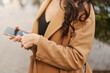 © olga pink - Young brunette businesswoman wearing beige coat using smartphone at the city.