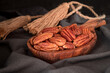 Pecan nuts in wooden bowl over wooden background