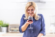 © weyo - Smiling woman smells the red wine poured in the glass at home