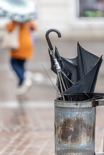 Umbrella Damaged By The Wind Gust Is Thrown Into A Street Bin On A Rainy Autumn Day