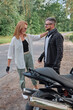 © perfectlab - Middle age couple talking and having fun on a motorcycle, traveling together on a forest road