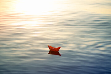 Wall Mural - A small handmade paper boat floating on the water