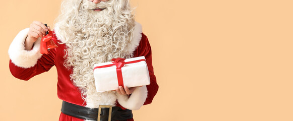 Santa Claus holding Christmas bell and present on beige background with space for text