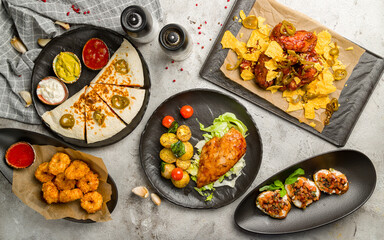 Wall Mural - chicken wings in barbecue sauce , chicken breast, quesadilla with chicken, cheese balls, bruschetta with tomatoes and cheese top view on grey table