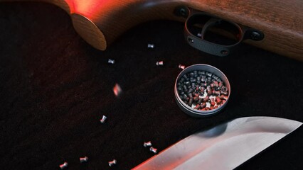 Wall Mural - Rifle air gun with air pellets for hunting on cloth dark background with knife and flashlight. Falling air gun pellets diabolo bullets.