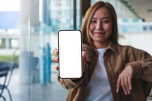 Mockup Image Of A Young Woman Holding And Showing A Mobile Phone With Blank White Screen
