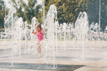 Child Playing With Water In A Dry Fountain On The Urban Plaza