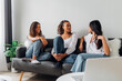 © Westend61 - Multiracial friends talking and sitting on couch at home