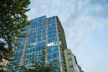 Wall Mural - Glass facade of buiding with green trees, Modern office building in city for business corporation, Residential contemporary