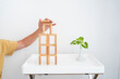 © Westend61 - Hand of man building wooden block tower on table