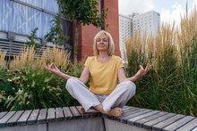 Mature Woman With Eyes Closed Meditating On Bench