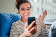 © Westend61 - Happy woman gesturing on talking video call through smart phone at home