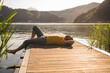 © Westend61 - Mature man relaxing on jetty over lake by mountains