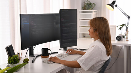Concentrated young female software developer working with coded data in bright modern office