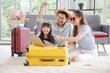 © aekkorn - Happy family tourist portrait. Father, mother and a daughter booking online air ticket, ready for travel with suitcase.
