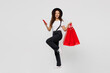 © ViDi Studio - Full body side view young woman wear t-shirt hat hold in hand red paper package bags after shopping use mobile cell phone isolated on plain solid white background. Black Friday sale buy day concept.