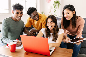 Young group of diverse students studying together using laptop at home - College multiracial people working on university group assignment homework project in modern apartment