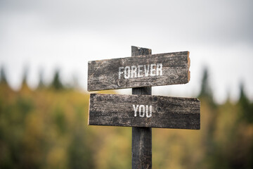 vintage and rustic wooden signpost with the weathered text quote forever you, outdoors in nature. bl
