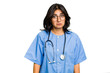 Young nurse Indian woman isolated shrugs shoulders and open eyes confused.
