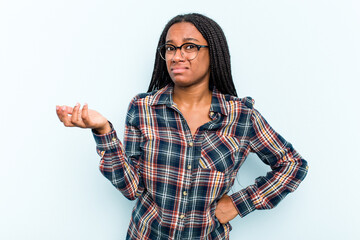 Wall Mural - Young African American woman with braids hair isolated on blue background doubting and shrugging shoulders in questioning gesture.