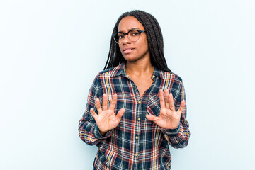 Wall Mural - Young African American woman with braids hair isolated on blue background rejecting someone showing a gesture of disgust.