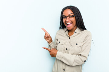 Wall Mural - Young African American woman with braids hair isolated on blue background excited pointing with forefingers away.