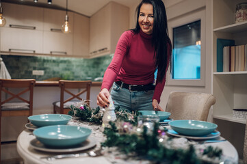 Wall Mural - Middle aged woman decorating and setting the table for Christmas dinner