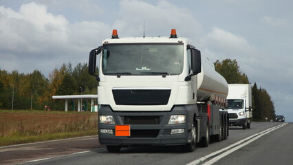 Wall Mural - White semi truck fuel tanker drive on suburban highway road at autumn day, front view, ADR cargo transportation logistics in Europe