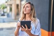 © Krakenimages.com - Young blonde woman drawing on touchpad with serious expression at street