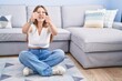 © Krakenimages.com - Young caucasian woman sitting on the floor at the living room angry and mad raising fists frustrated and furious while shouting with anger. rage and aggressive concept.