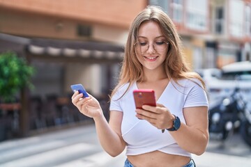 Sticker - Young blonde woman using smartphone and credit card at street