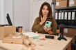 © Krakenimages.com - Hispanic woman working at small business using smartphone covering mouth with hand, shocked and afraid for mistake. surprised expression