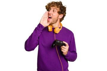 Young caucasian gamer man holding a game controller isolated on white background shouting and holding palm near opened mouth.