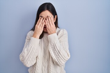 Poster - Young brunette woman standing over blue background rubbing eyes for fatigue and headache, sleepy and tired expression. vision problem