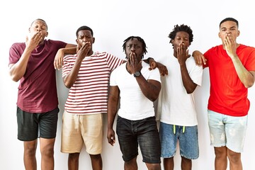 Poster - Young african group of friends standing together over isolated background bored yawning tired covering mouth with hand. restless and sleepiness.