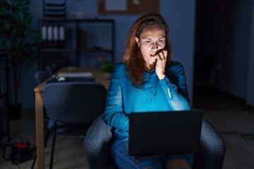 Sticker - Brunette woman working at the office at night looking stressed and nervous with hands on mouth biting nails. anxiety problem.