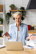 © ArtSys - Attractive senior woman working at home in the kitchen using her laptop for conference call. Concept of mature female using internet, modern technology for learning, shopping, freelance job