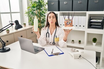 Wall Mural - Hispanic doctor woman holding model of human anatomical skin and hair making fish face with mouth and squinting eyes, crazy and comical.