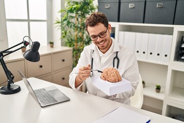 Sticker - Young hispanic man wearing doctor uniform having video call holding brain at clinic