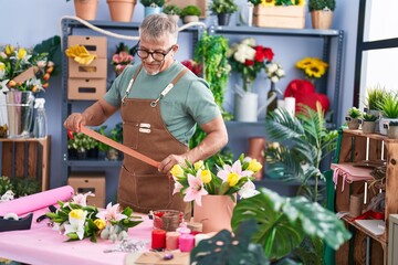 Poster - Middle age grey-haired man florist holding lace at flower shop