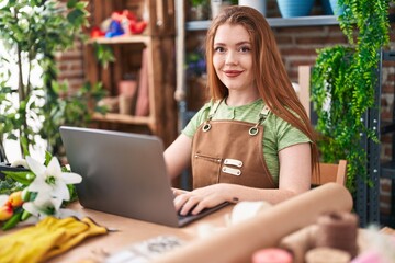 Wall Mural - Young redhead woman florist smiling confident using laptop at flower shop