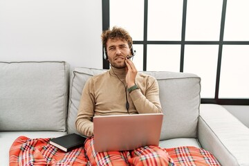 Poster - Young handsome man with beard wearing operator headset working from home touching mouth with hand with painful expression because of toothache or dental illness on teeth. dentist concept.