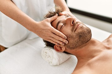 Poster - Young hispanic man having facial massage at beauty center