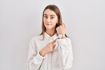 Sticker - Young caucasian woman standing over isolated background in hurry pointing to watch time, impatience, looking at the camera with relaxed expression