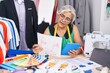 © Krakenimages.com - Middle age grey-haired woman tailor using touchpad looking clothing design at tailor shop