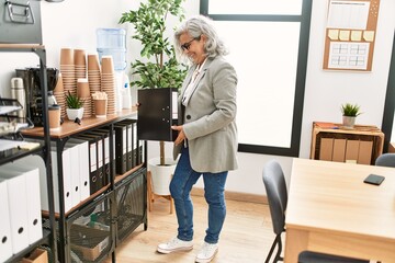 Canvas Print - Middle age grey-haired businesswoman smiling happy working at the office.