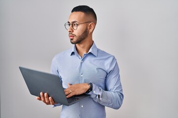 Canvas Print - Young hispanic man working using computer laptop looking to side, relax profile pose with natural face and confident smile.