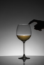 Woman Posing Her Finger On The Rim Of The Glass Of White Wine. Black Silhouette.