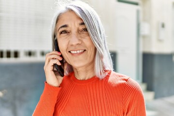 Middle age grey-haired woman smiling happy talking on the smartphone at the city.