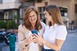 © Krakenimages.com - Mother and daughter using smartphone standing together at street